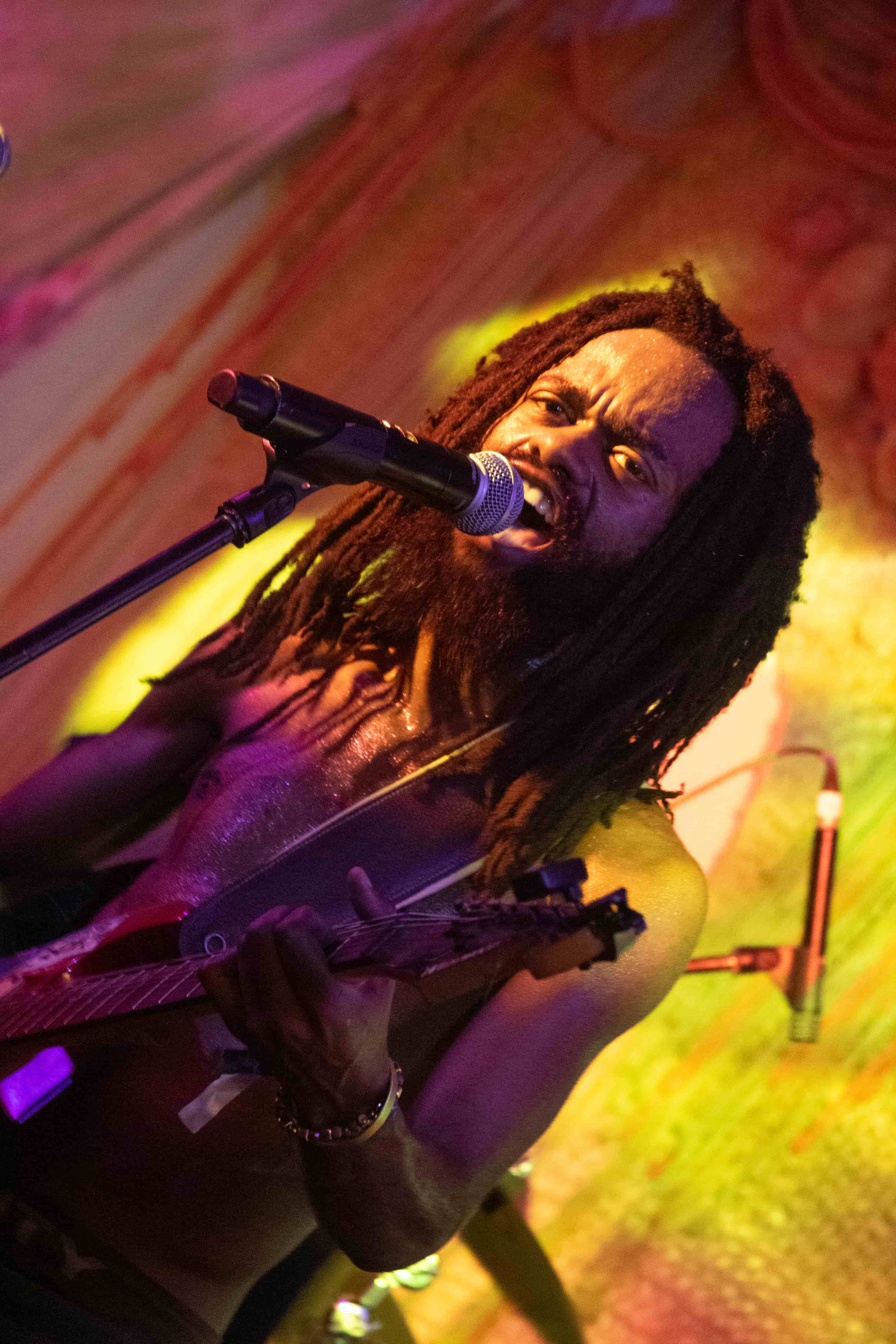 Sanele Blaai singing and playing guitar under colourful lights