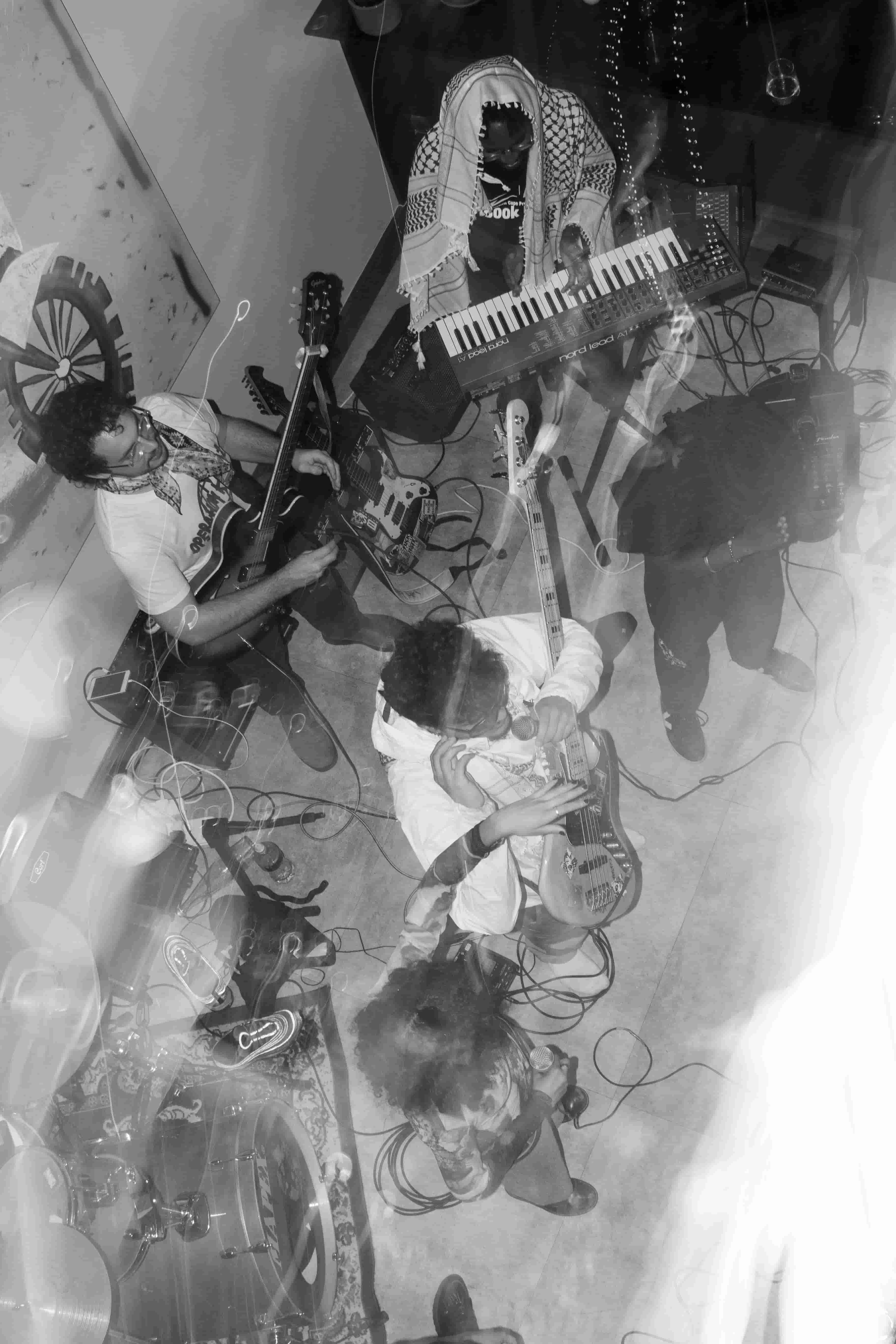 Overhead double-exposure shot of band rehearsing, black and white