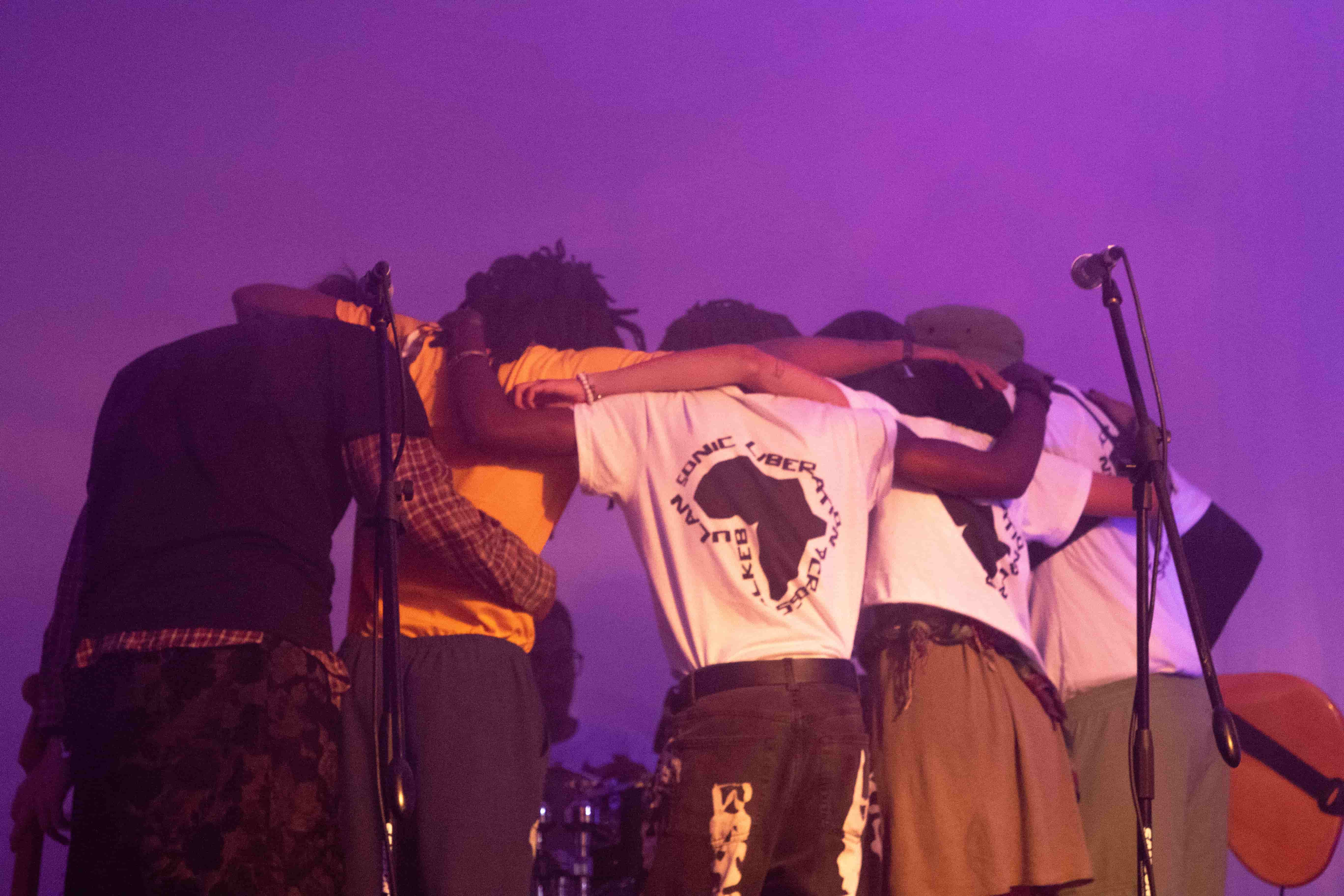 Band in huddle on stage under purple light